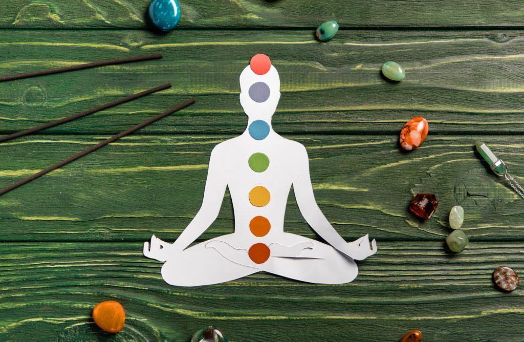 top view of paper figure in form of person with chakras in lotus pose, aroma sticks and colorful