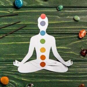 top view of paper figure in form of person with chakras in lotus pose, aroma sticks and colorful