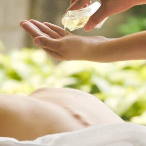 Massage therapist pouring essential oil for massage at spa.