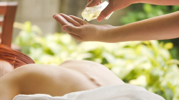 Massage therapist pouring essential oil for massage at spa.