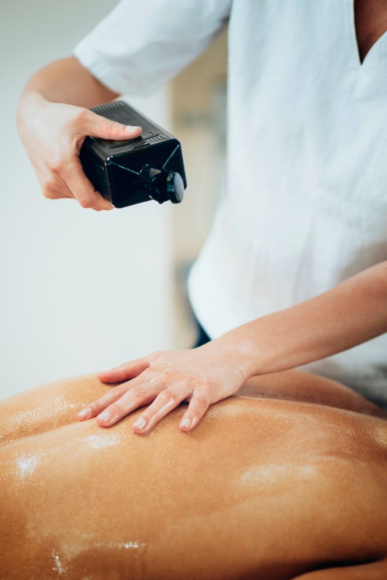 Sports massage. Therapist pouring massage oil