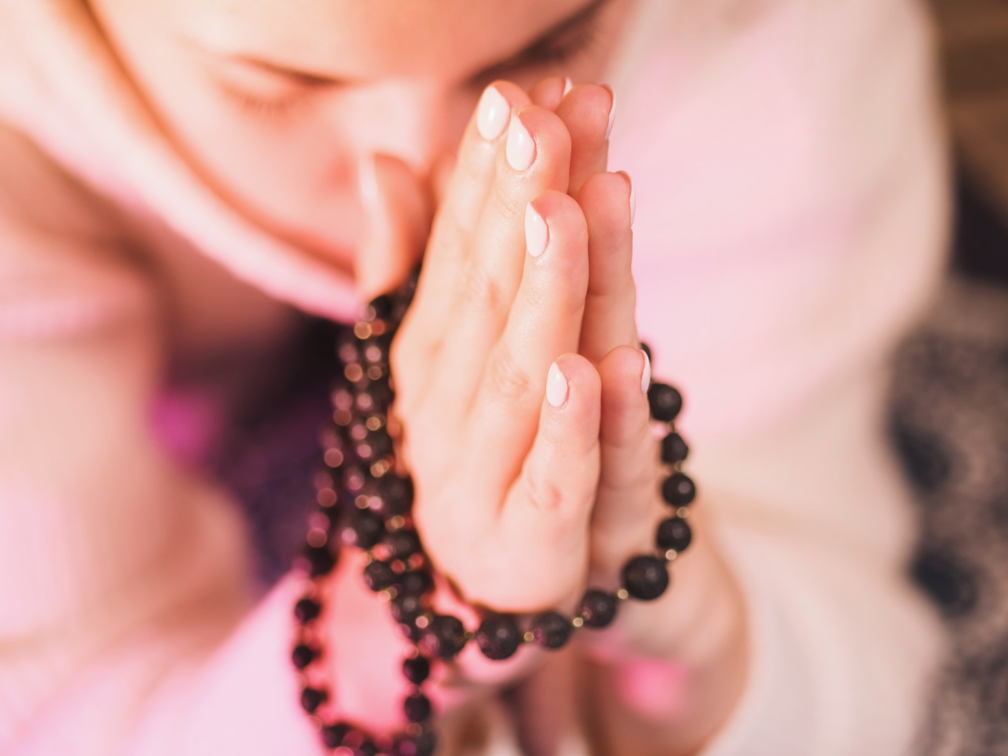 Woman holding mala beads in hand. Counting beads and reading mantra