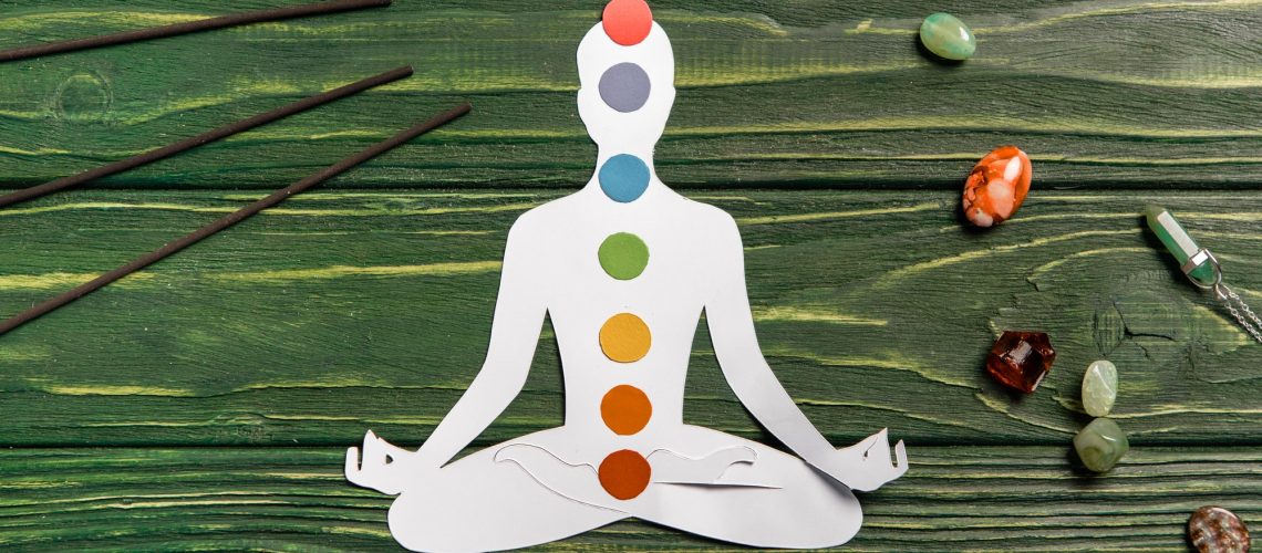 top view of paper figure in form of person with chakras in lotus pose, aroma sticks and colorful