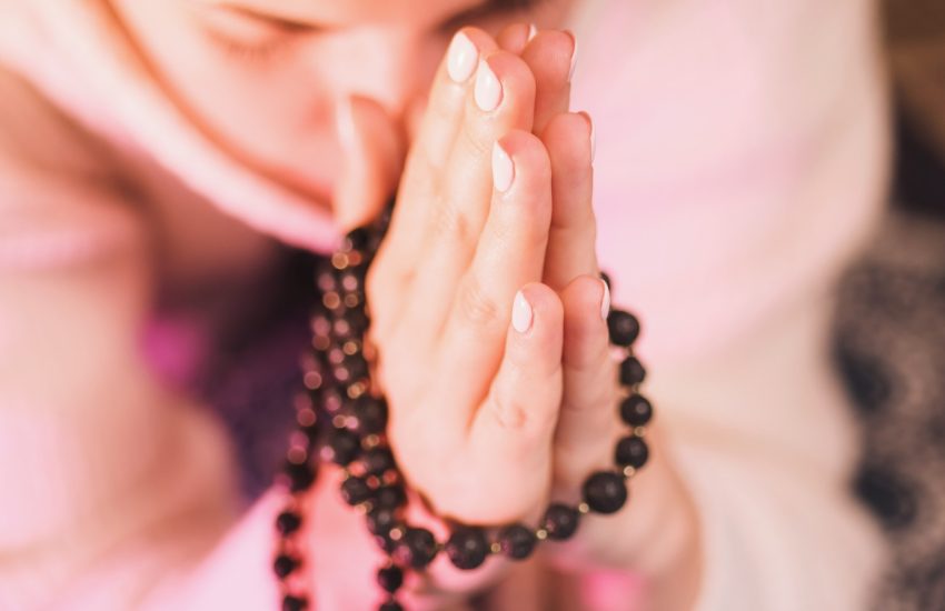 Woman holding mala beads in hand. Counting beads and reading mantra