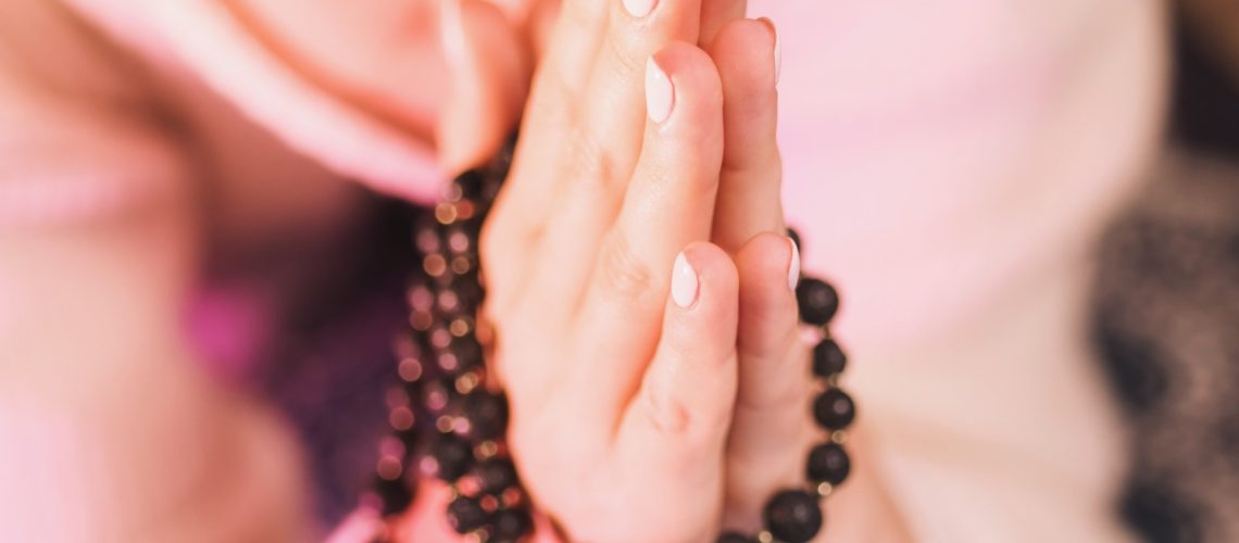 Woman holding mala beads in hand. Counting beads and reading mantra